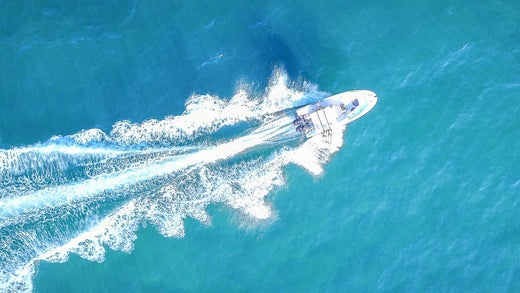 A boat from above cutting through the ocean and leaving a wake.