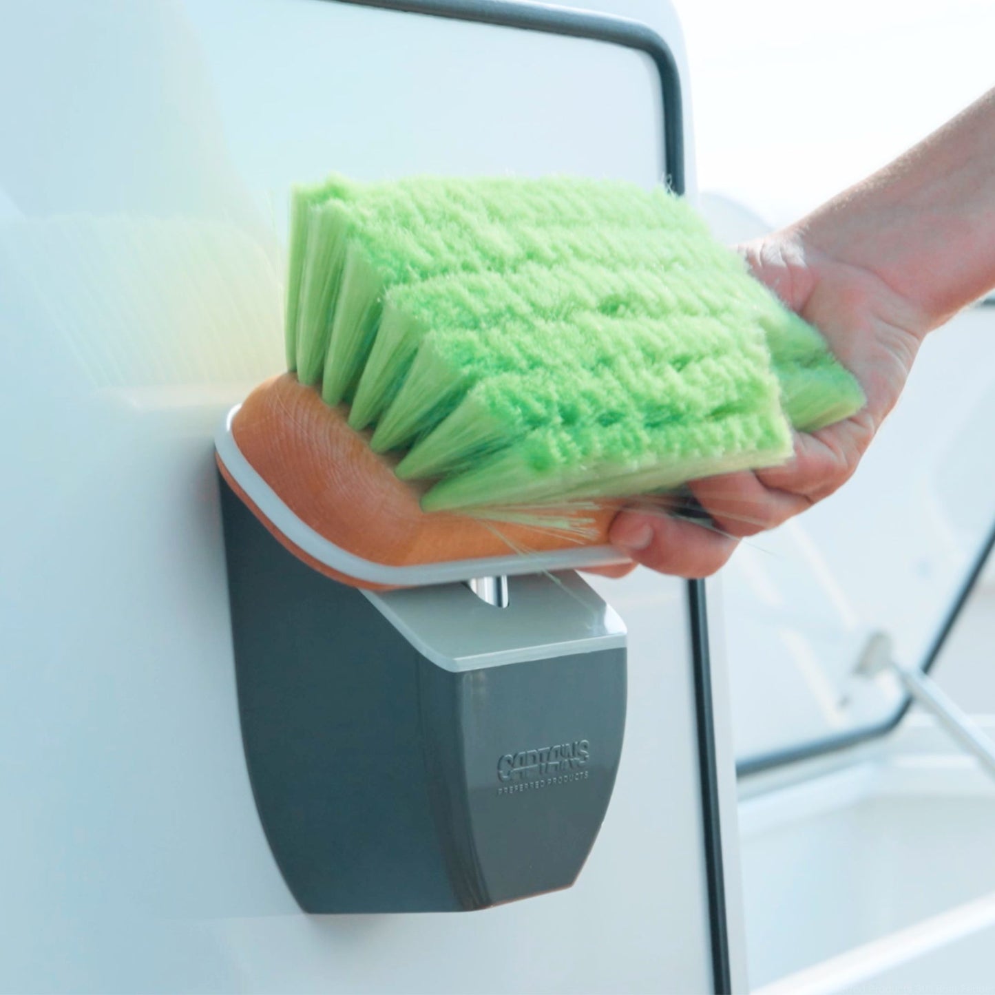 A boat brush holder installed on the inside of a door of a boat with a green boat brush.
