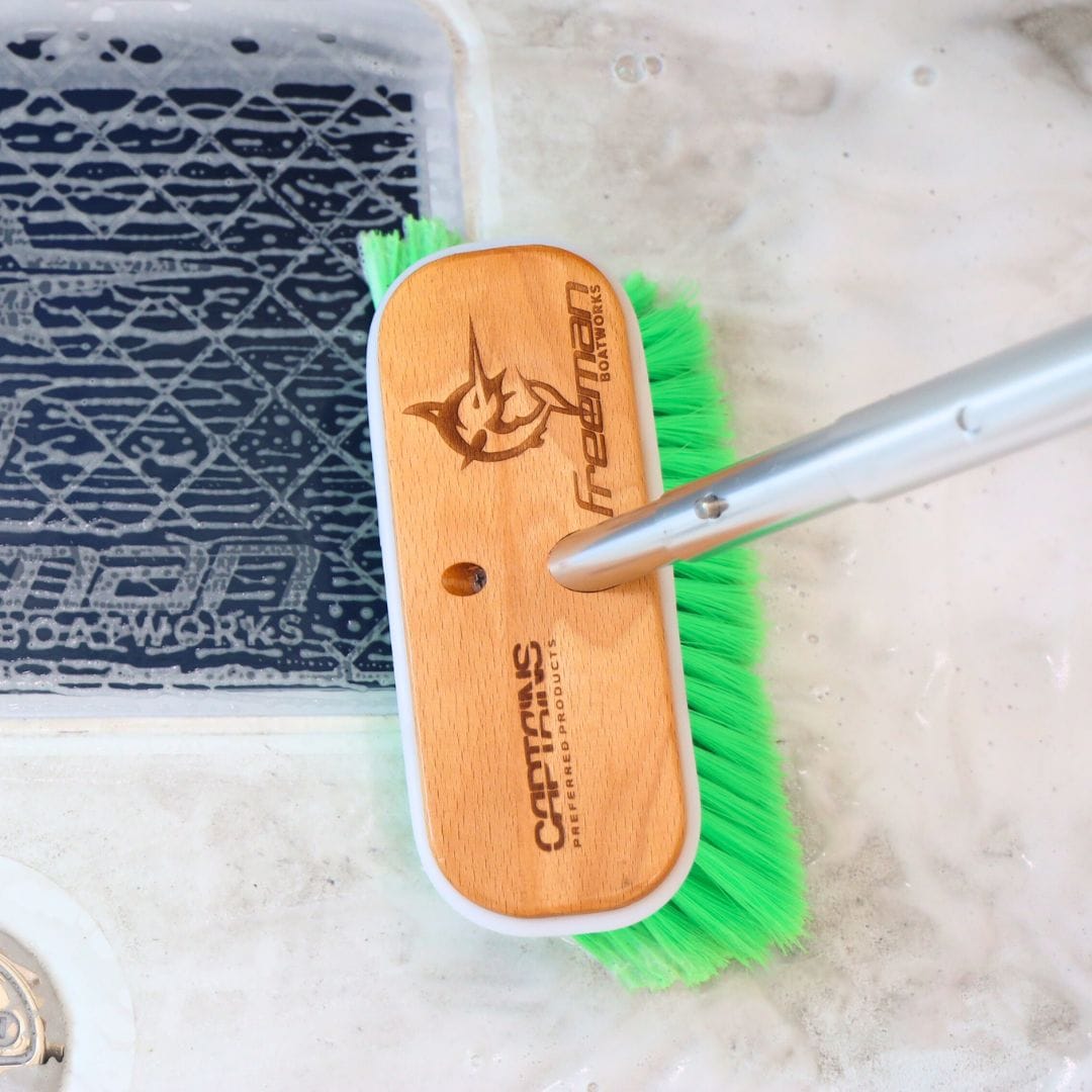 Close up of the wooden head of a boat scrub brush with a Freeman Boatworks logo laser etched in the brush.