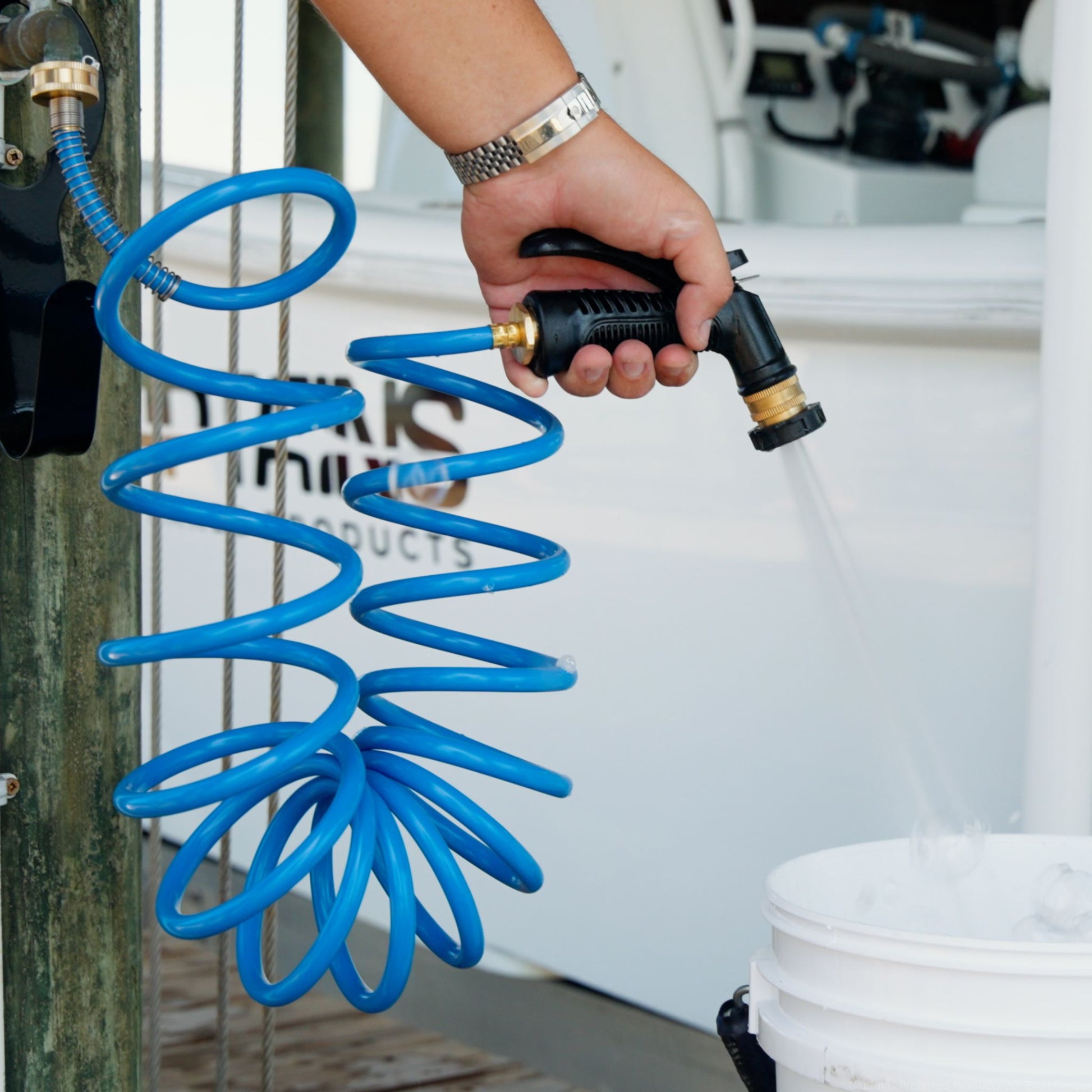 A blue washdown hose by Captains Preferred Products used to fill a bucket at the dock.