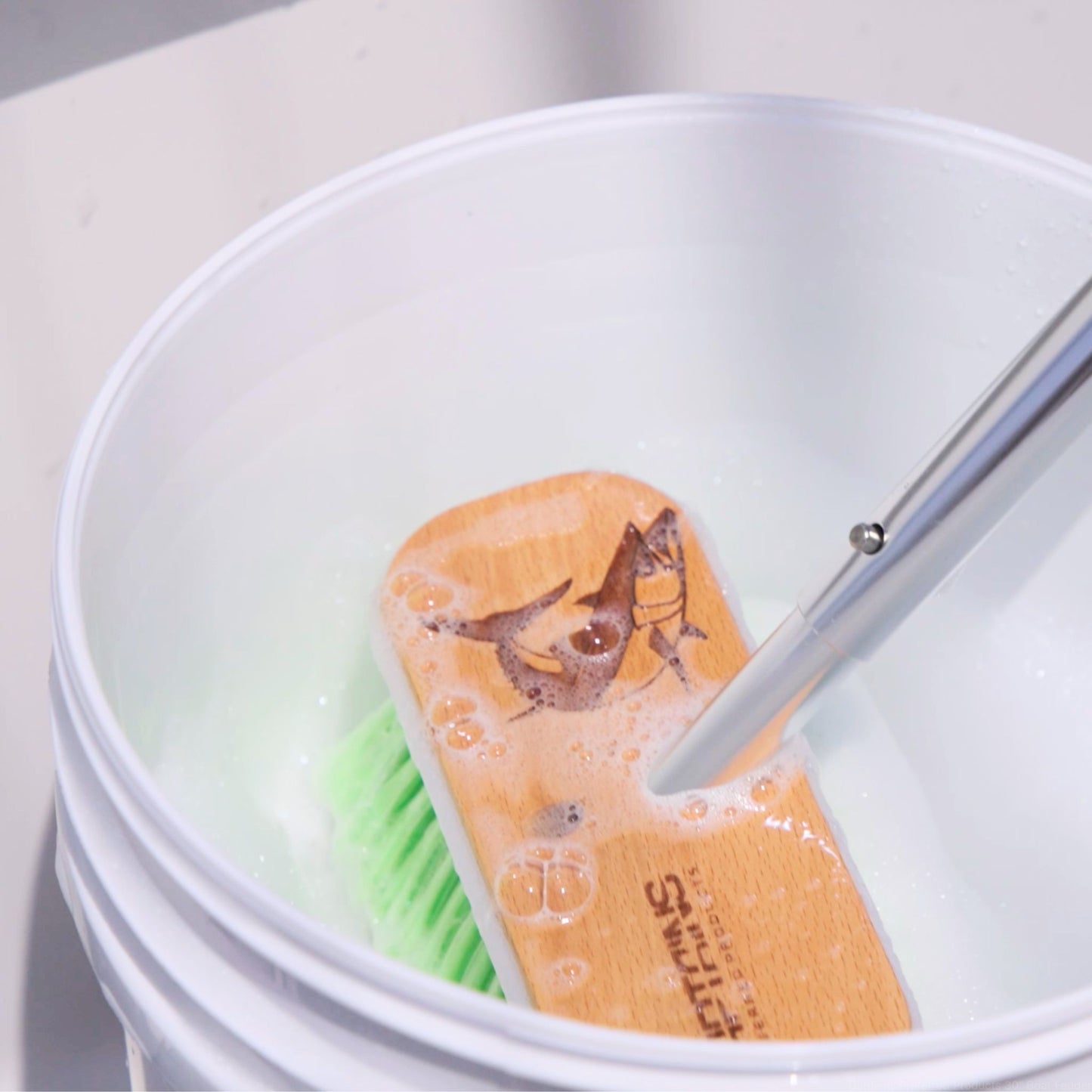 A custom boat brush being used with boat soap in a bucket.