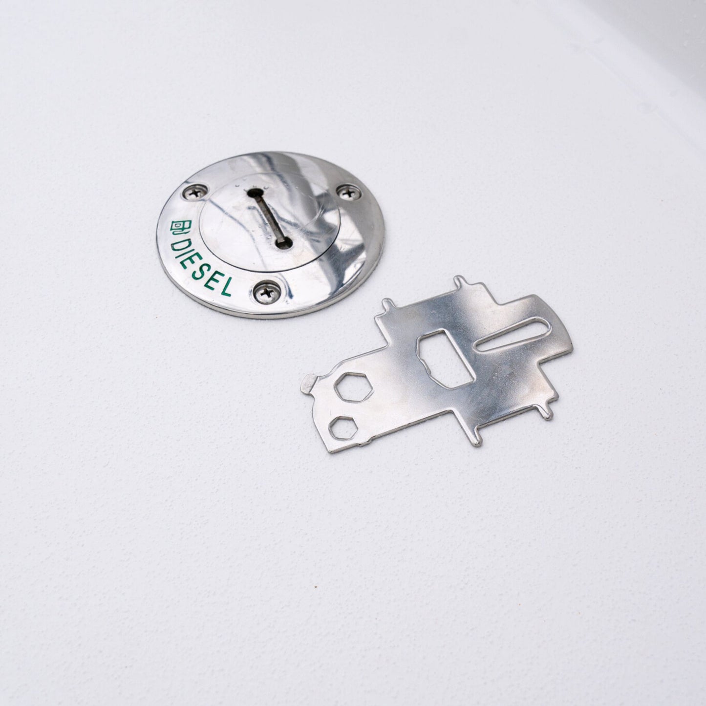 Captains' universal deck plate key next to a diesel fuel cap on a boat.