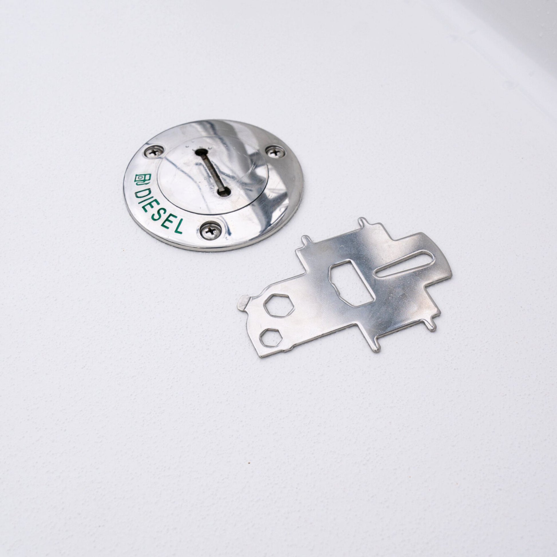 Captains' universal deck plate key next to a diesel fuel cap on a boat.