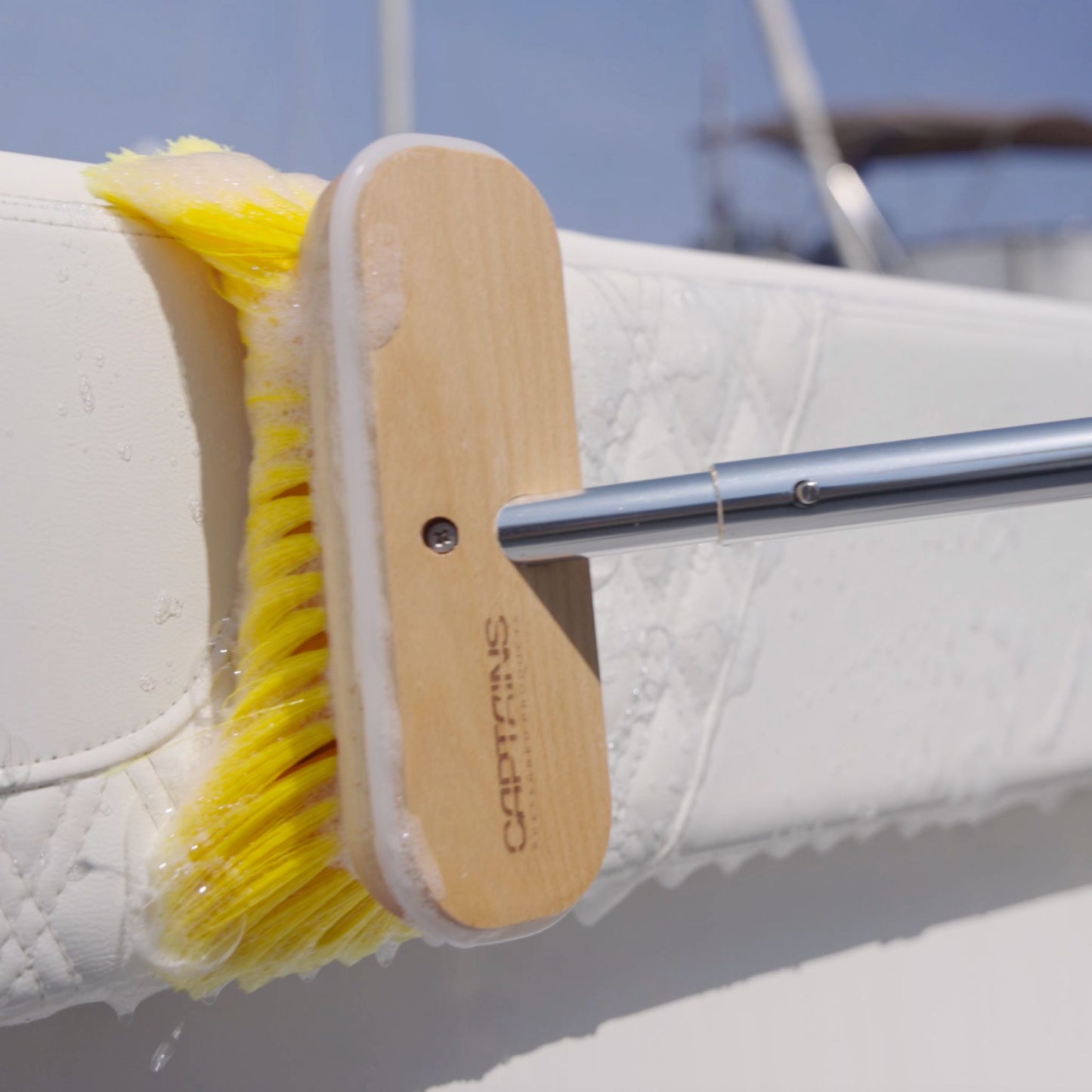 Yellow boat brush scrubbing boat vinyl.