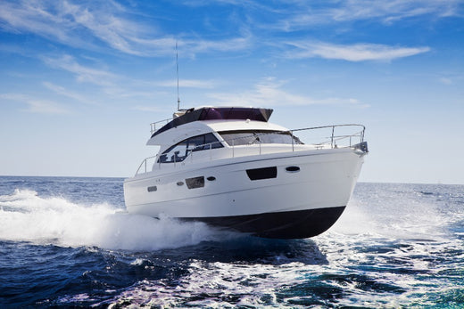 A large boat cutting through the water with blue skies.