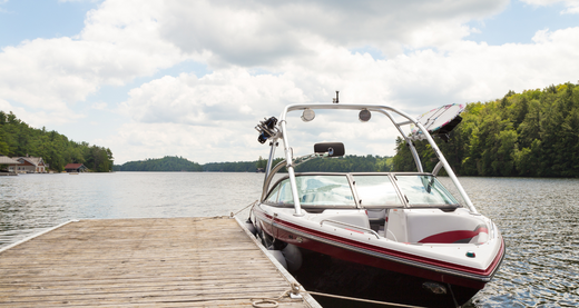 A speedboat tied to the dock on a lake.