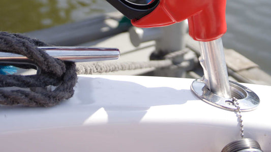 A red fueling pump inserted into the fuel tank of a boat.