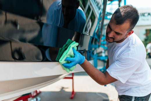 A boat detailer polishes the hull of a boat with a microfiber cloth.