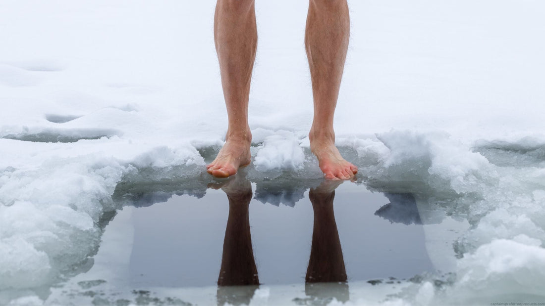 A person stands at the edge of a hole in the ice preparing to submerge in the water.