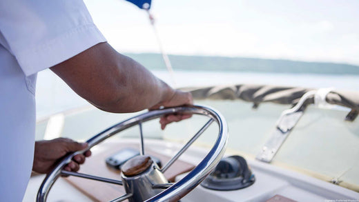 A boat captain steering at the wheel of a boat.