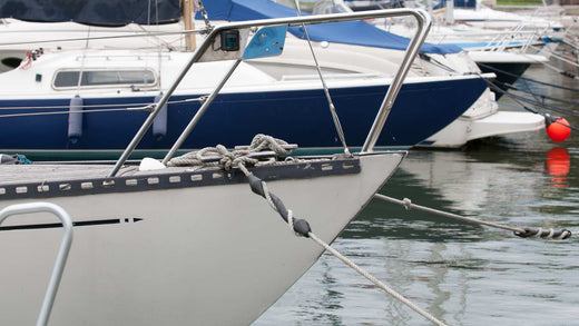 A line of boats tied to a dock using assorted dock lines.