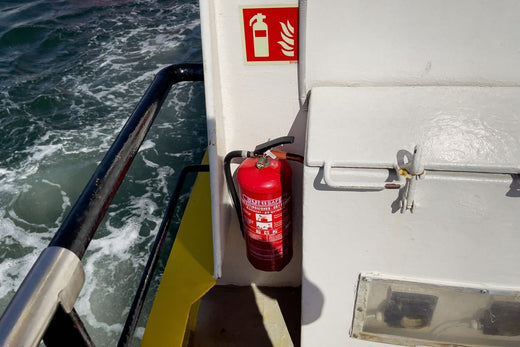 A red fire extinguisher attached to the side of a boat.