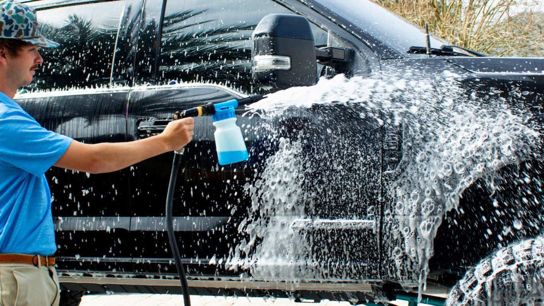 A foam cannon spraying thick foam on a big black truck.