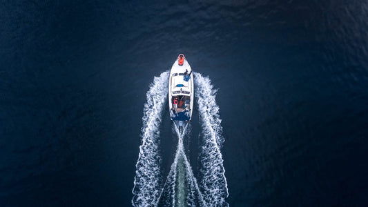 A boat viewed from the top cuts through deep blue waters.