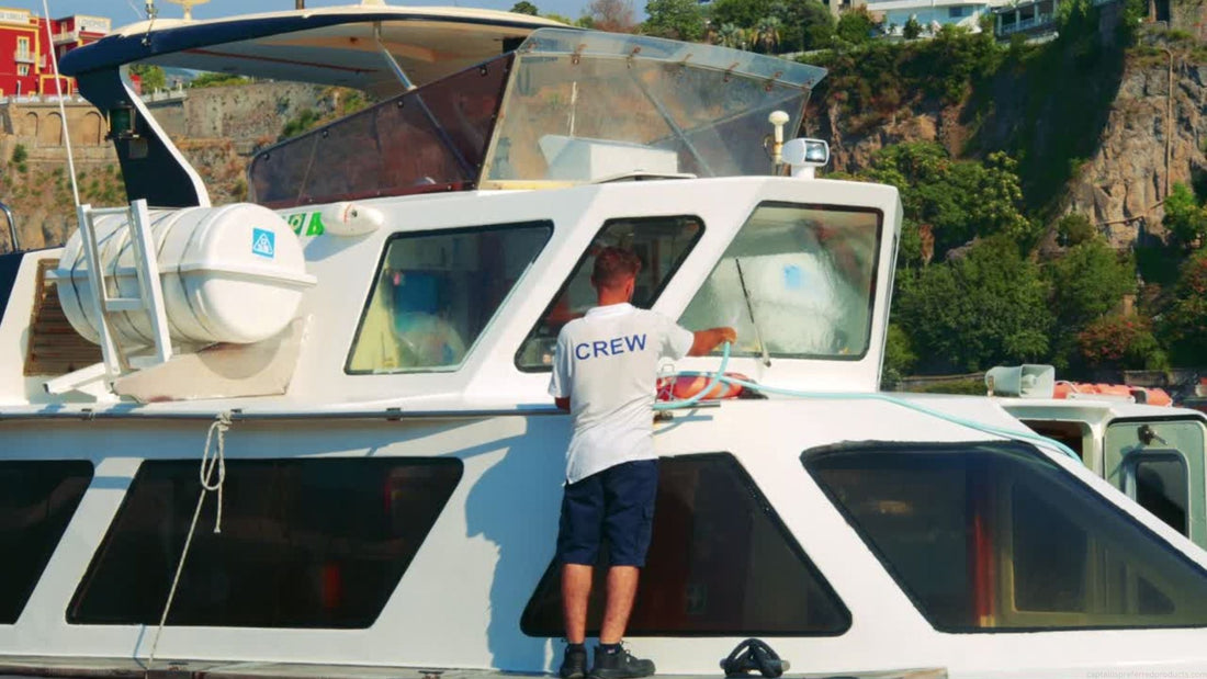 A man hoses off a large boat as part of a cleaning routine to keep the boat maintained.