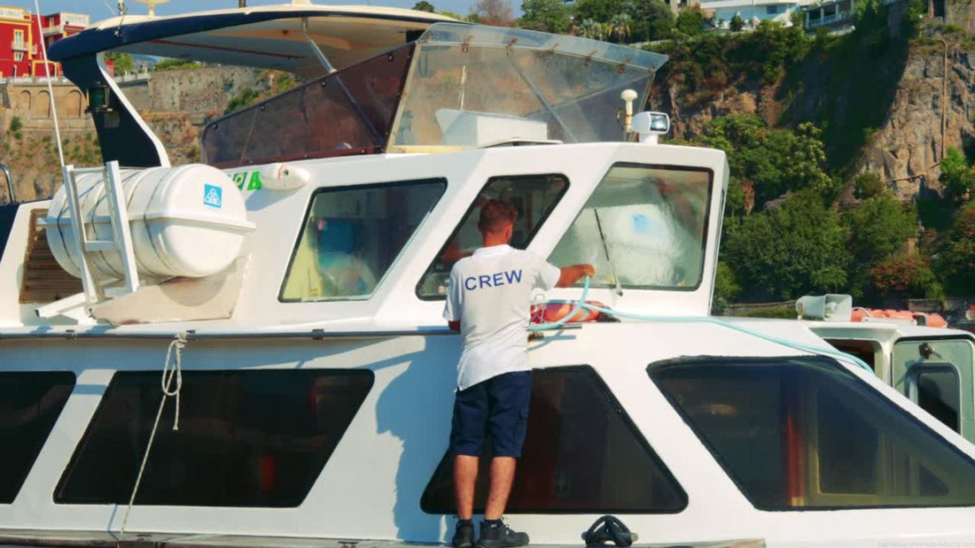 A man hoses off a large boat as part of a cleaning routine to keep the boat maintained.