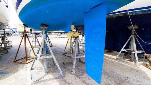 The large blue keel of a boat that is sitting on stilts for maintenance.