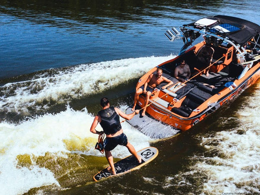 A wake boarder being pulled by an orange wake boat.