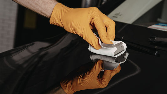 A detailer applies an siO2 coating to a black car surface.
