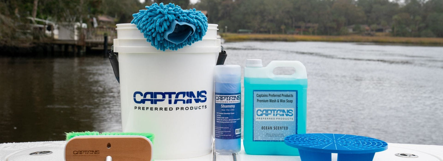 A boat cleaning kit sitting on the side of a boat by the water.