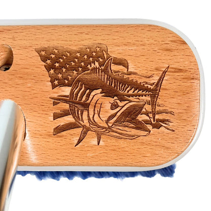 A mackerel fish in front of a waving American flag etched into a deck brush.