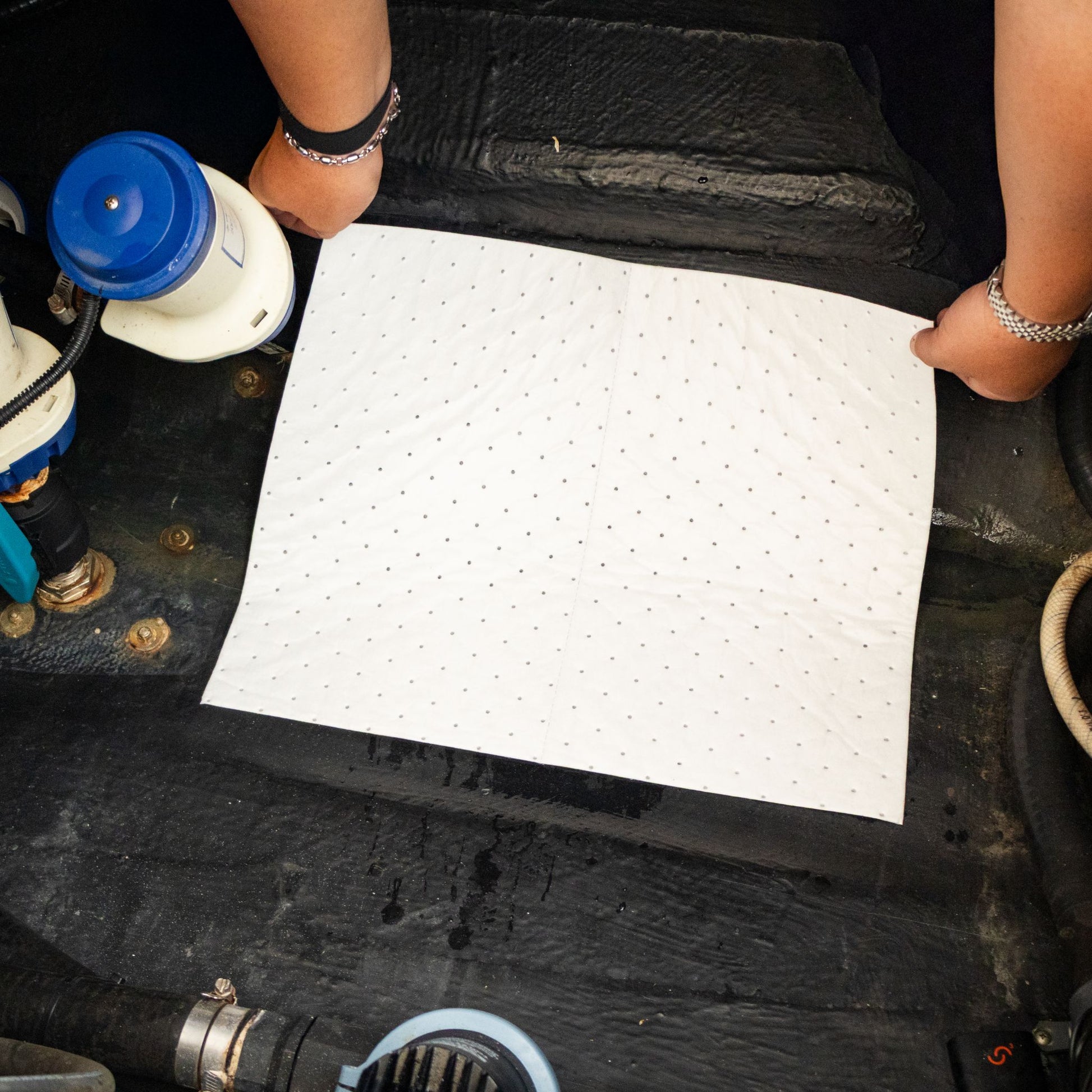 A man places an oil absorbent pad in the bilge of his boat.
