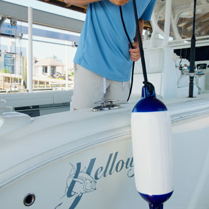 A boat fender being lowered down from a boat deck.