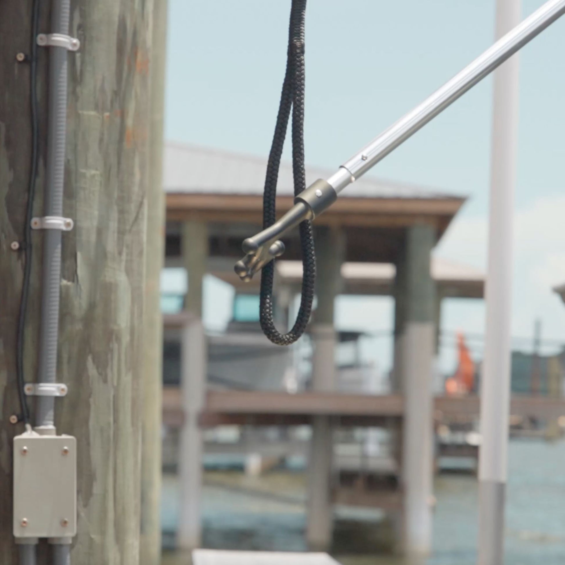A boat hook grabbing the end of a dock line. 