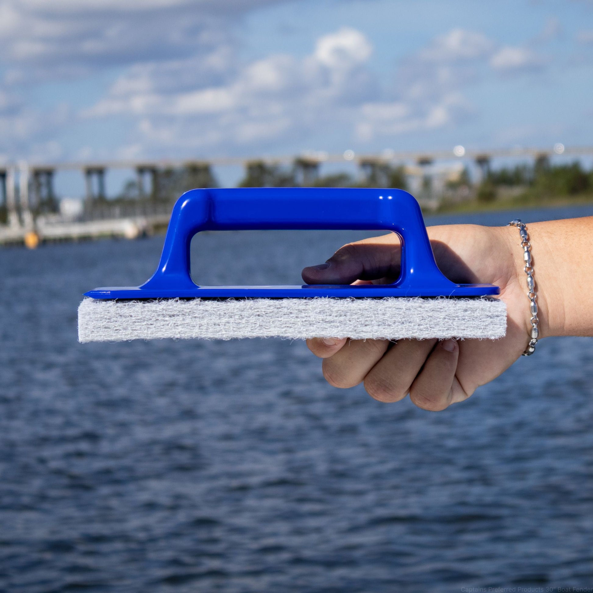 Profile view of a large scrub pad with blue handle.