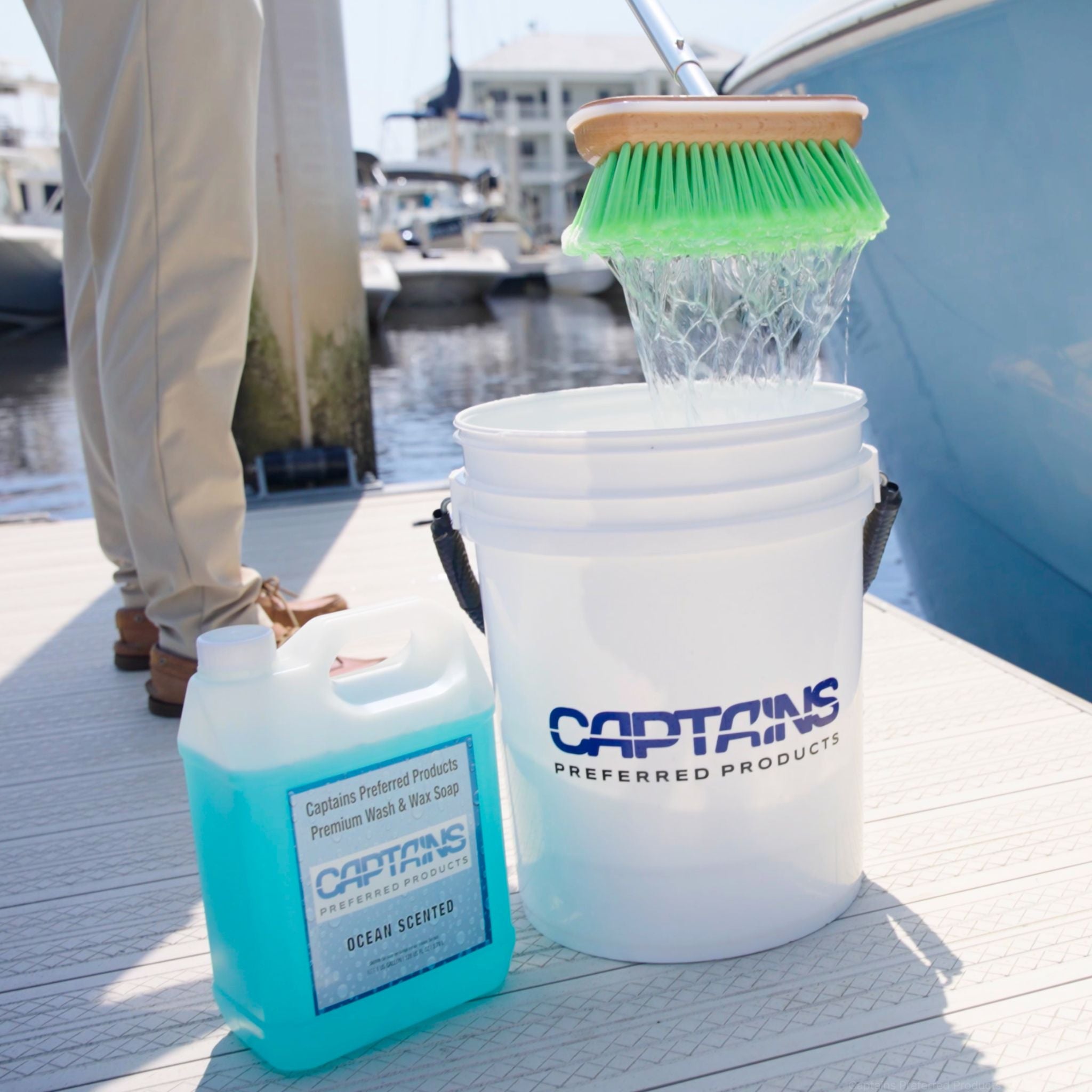 A boat brush being dunked into a 5-gallon bucket of boat soap.