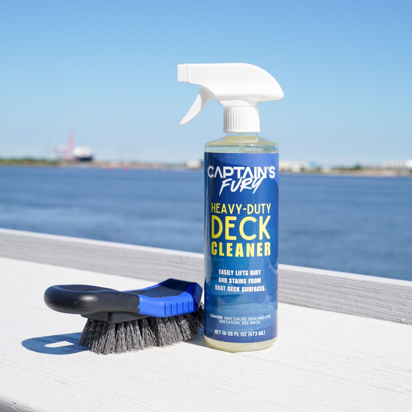 Boat deck cleaner and scrub brush with water in the background.