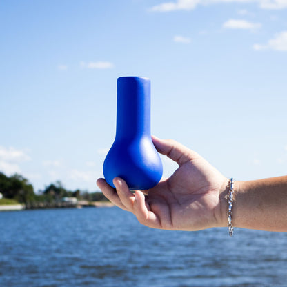 A hand holds a blue fishing rod cushion with water in the background.