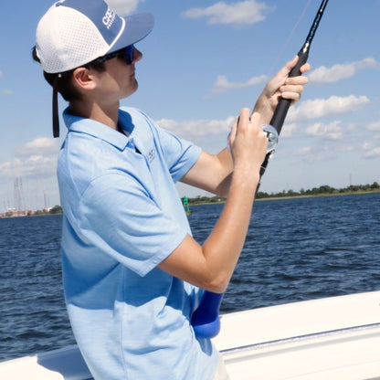 A man using a fishing rod cushion to brace while reeling.