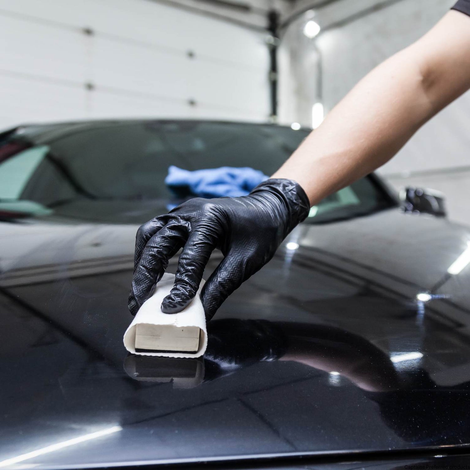 A ceramic coating being applied to a shiny car surface.