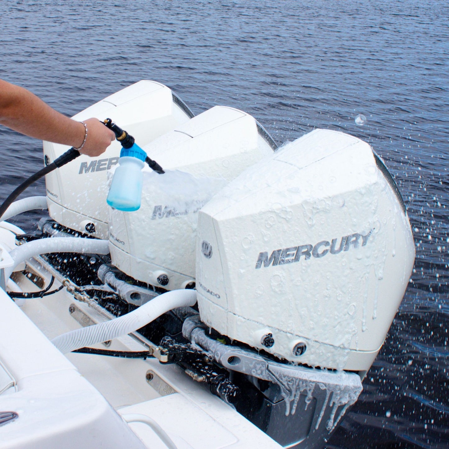 A foam cannon spraying foamy soap on Mercury boat motor cowlings.