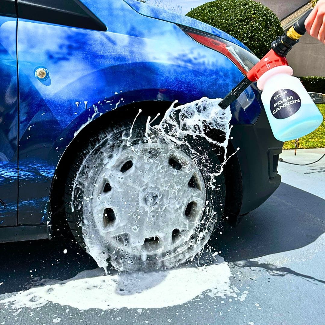 A car tire being sprayed with lots of foam from a foam cannon.