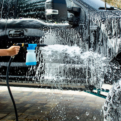Person washing a black truck with a Captains Preferred foam cannon, surrounded by soap suds.