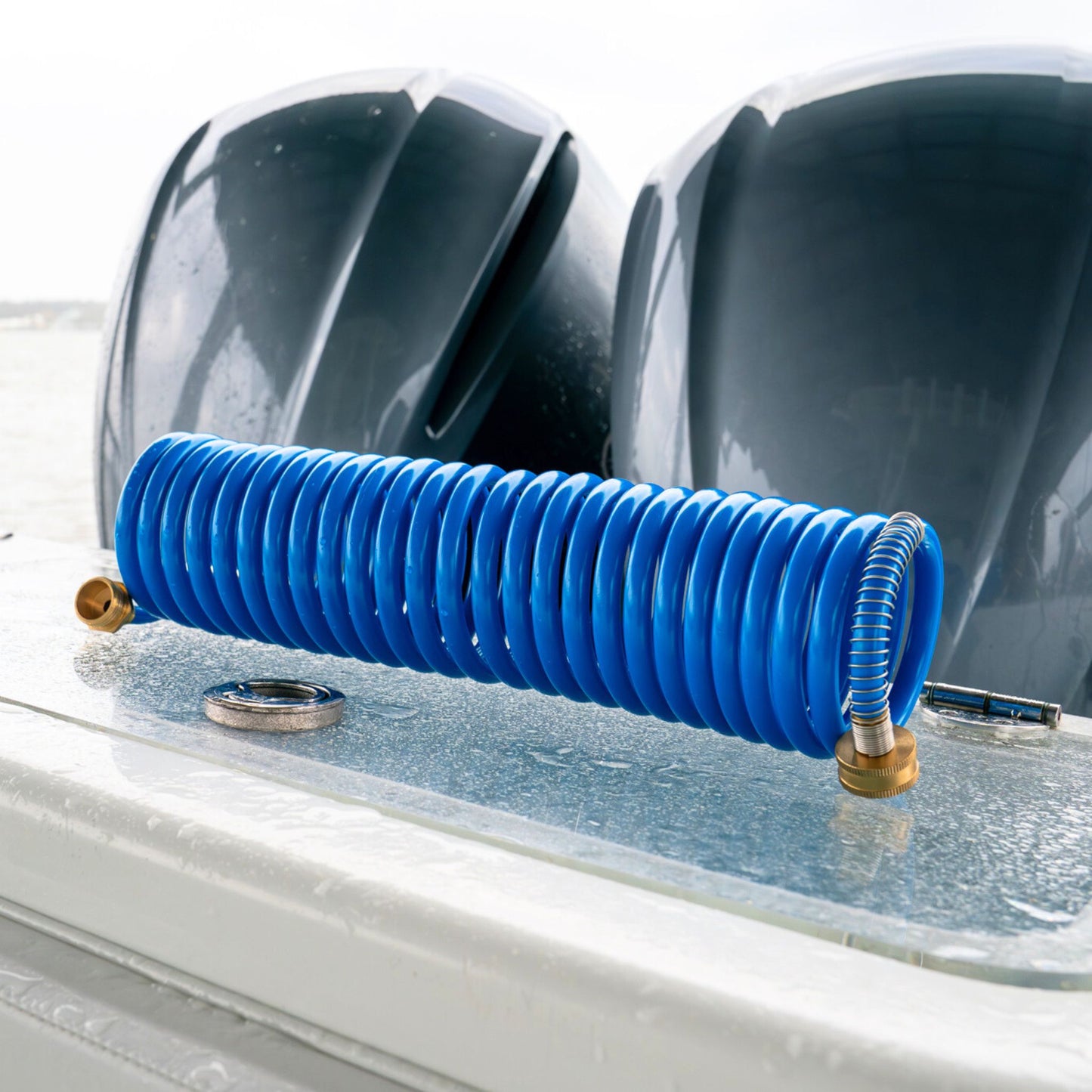 A coiled boat washdown hose from Captains Preferred Products sits on a boat transom near the engines.