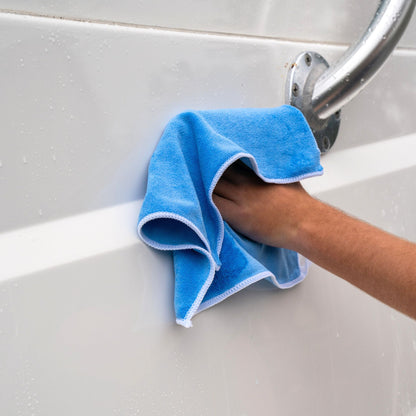 A blue microfiber rag being used to dry a wet boat.