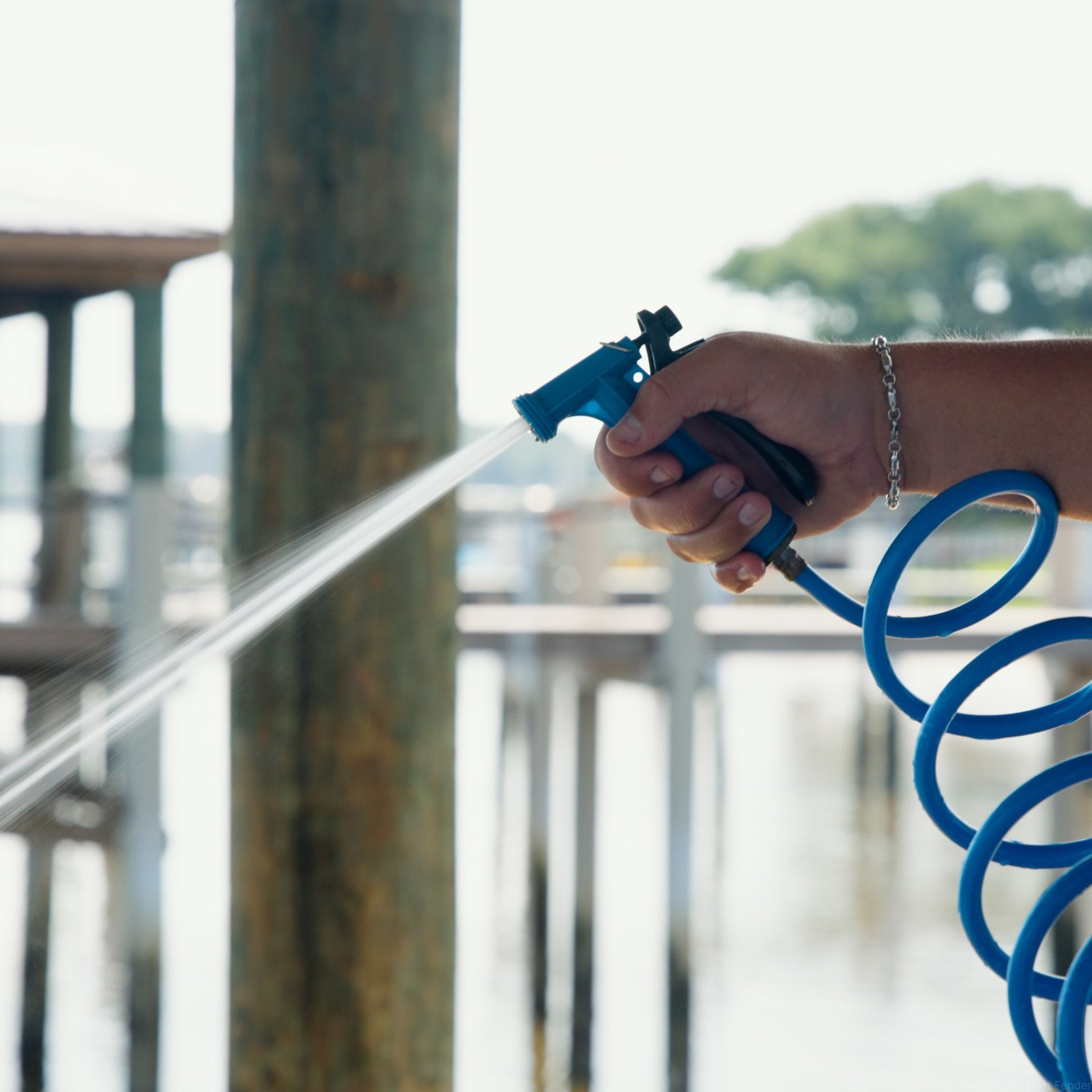 A washdown hose and nozzle being used to spray down a boat at the dock.