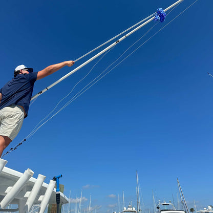 Using a chamois mop with extendable handle to dry the outrigger on a boat.