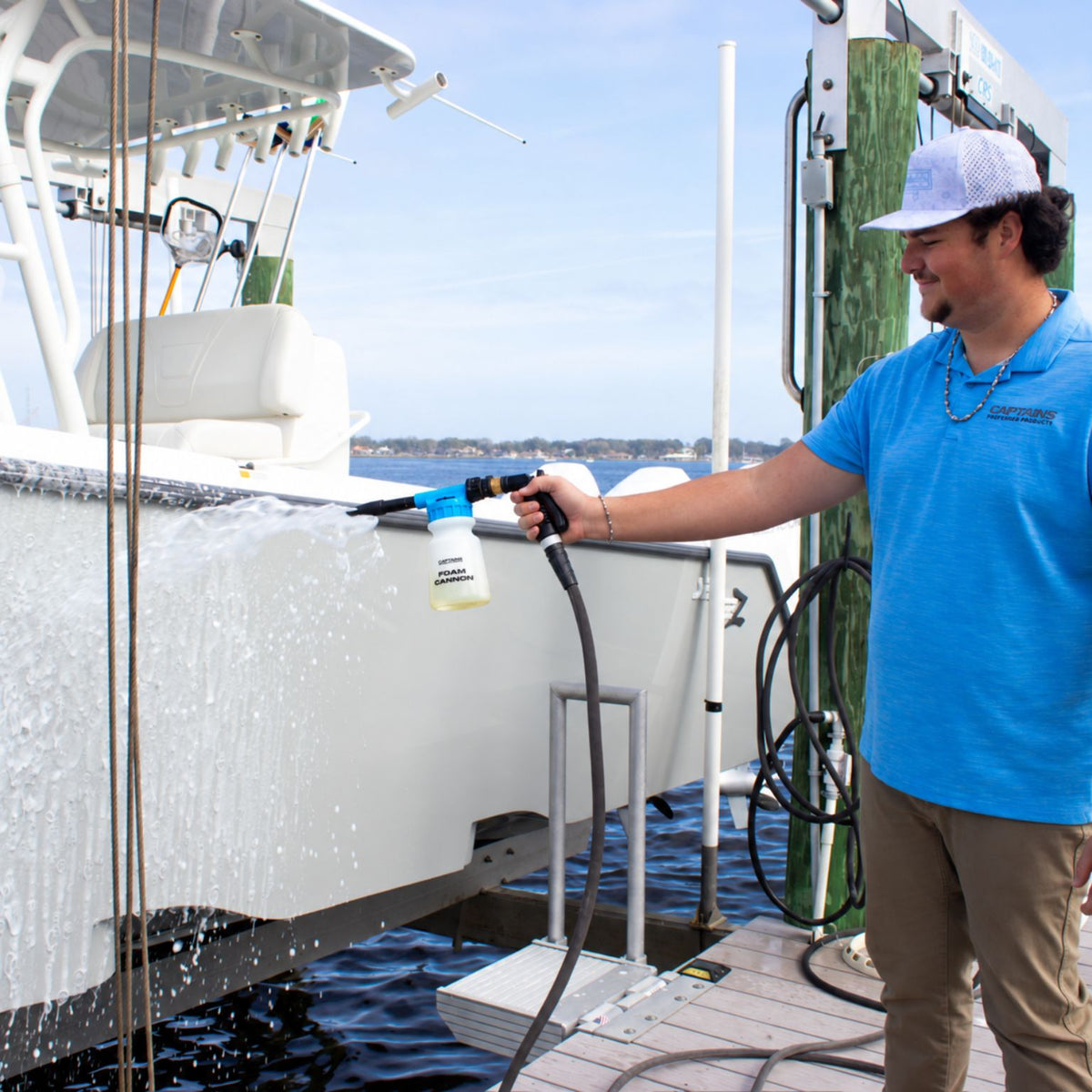 A man sprays Captain's Fury Salt Remover Soap from a foam cannon to wash his boat.