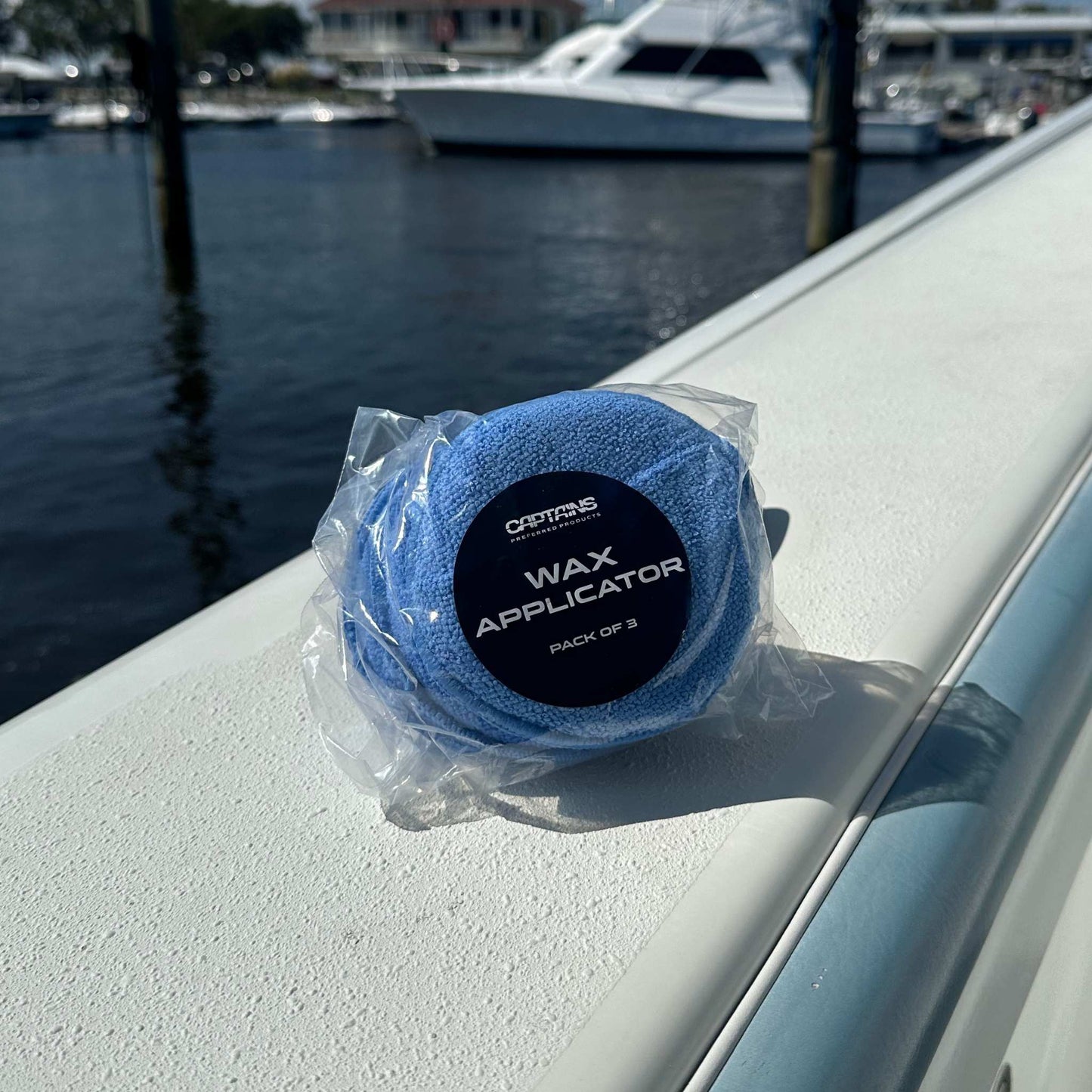 A 3 pack of Captains' Preferred Products wax applicator pads on the edge of a boat in the water.